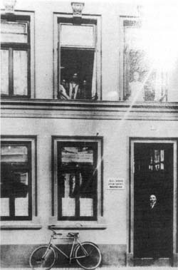 Anna Netheim mit den Kindern im mittleren Fenster, in der Haustür der Ehemann Julius   